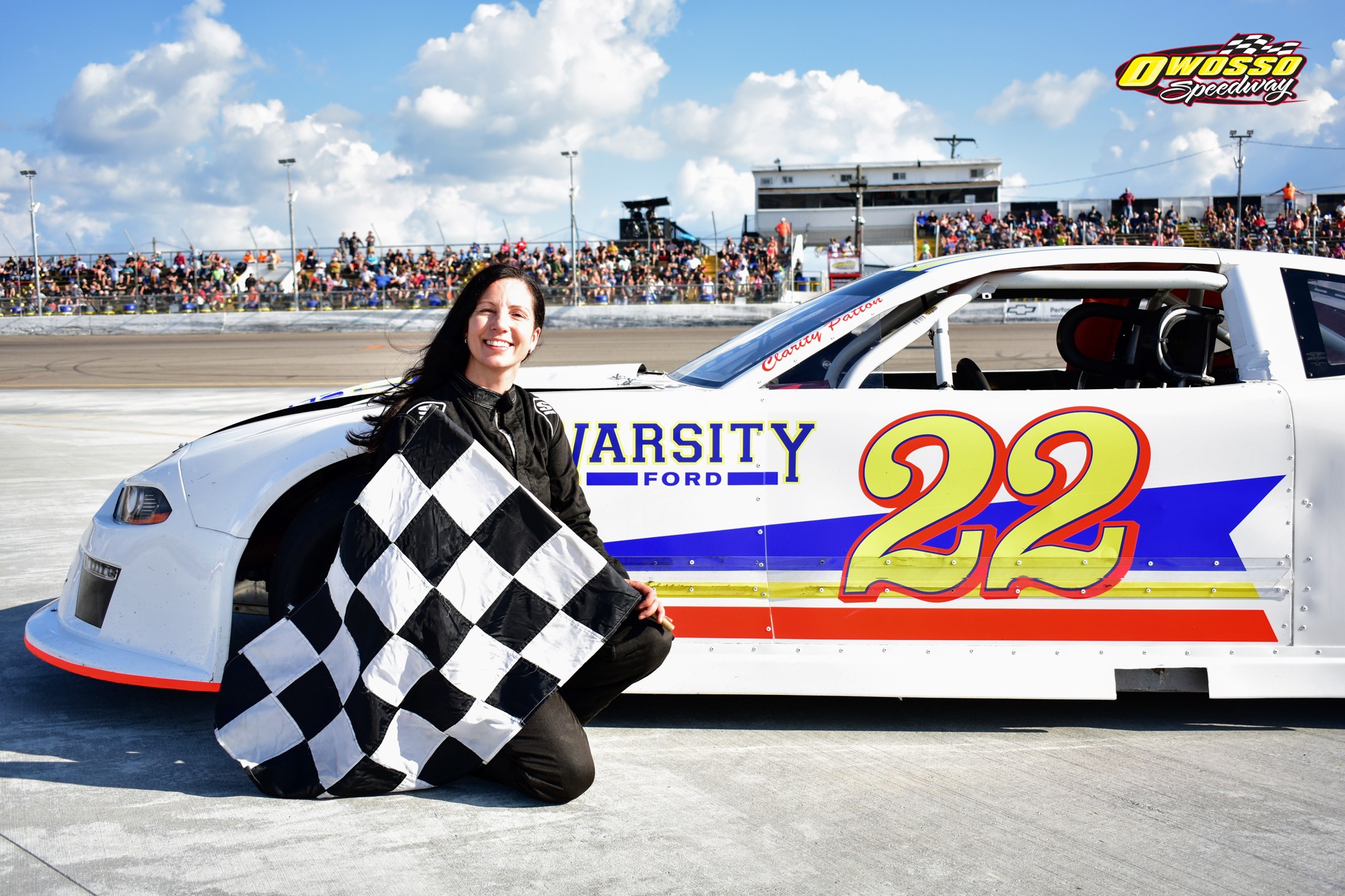 Clarity Patton beside the number 22 race car with a checkered flag